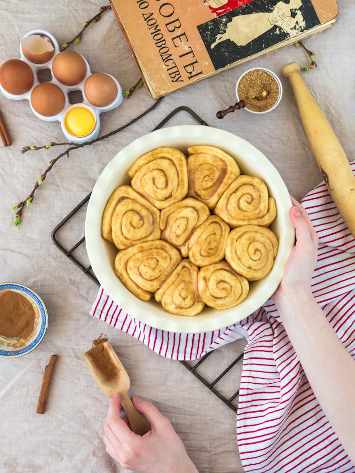 Top view of homemade cinnamon rolls with ingredients on a table, showcasing the baking process.